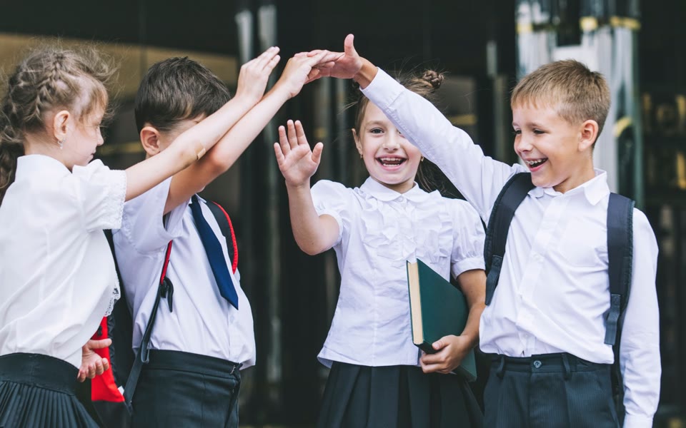 Primary school pupils high-fiving outside school